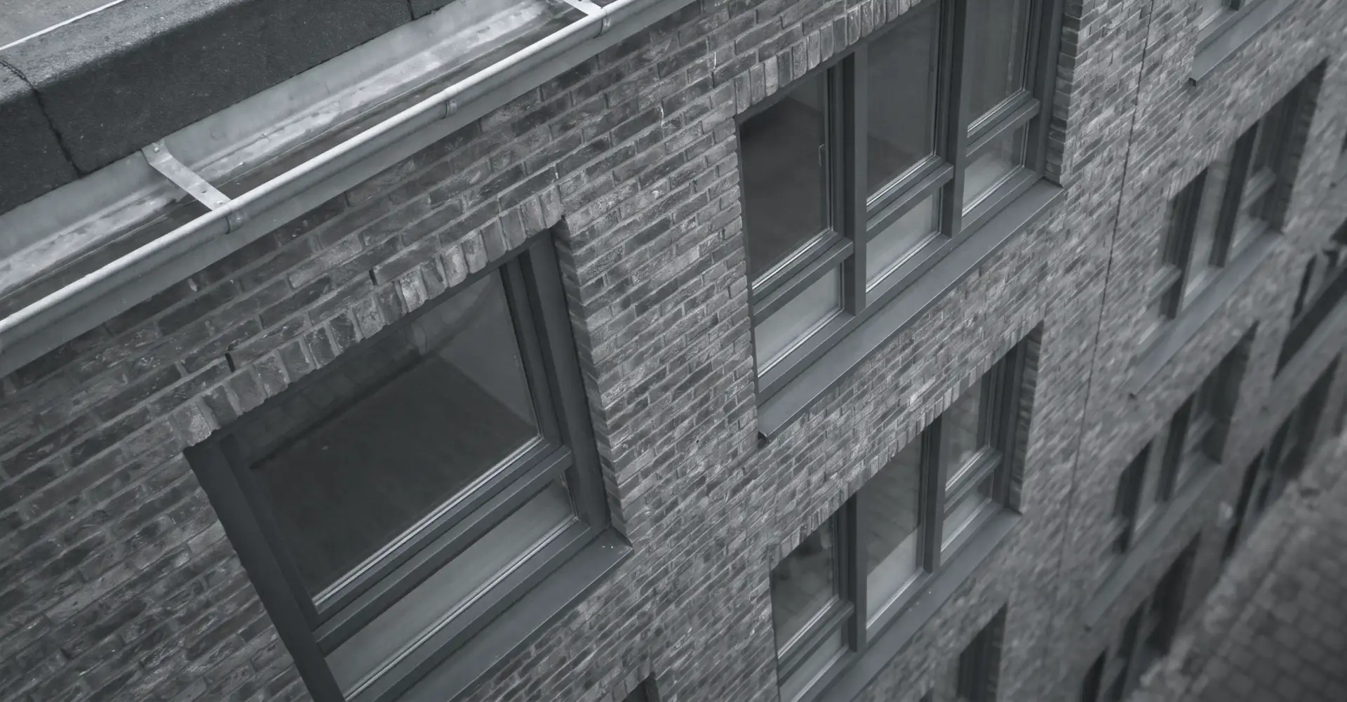 Luchtopname van een bakstenen gevel en dakrand, gezien vanaf een inspectiedrone boven het gebouw.